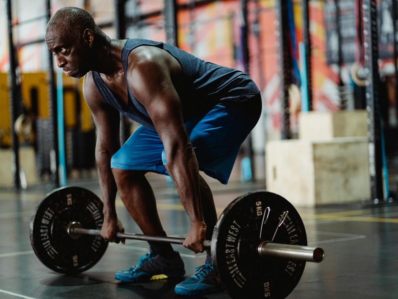 Athletic man performing strength exercises in a bright room.